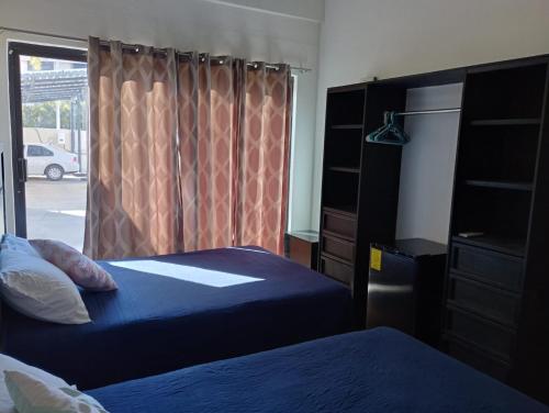 a bedroom with two beds and a window with a dresser at Hostal las Quintas in San José del Cabo
