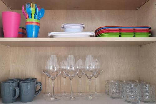 a row of wine glasses and plates on a shelf at H&H New Built 2023 Hidden Gem Heart of OC 3 Queen Beds in Westminster