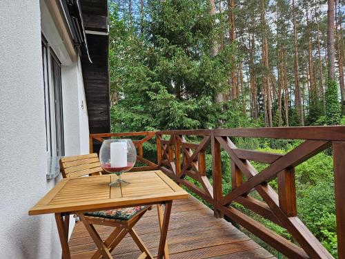 a wooden table with a glass of wine on a balcony at Ferienhaus JULKA am See mit Kamin & WLAN - Domek Letniskowy JULKA in Teerau