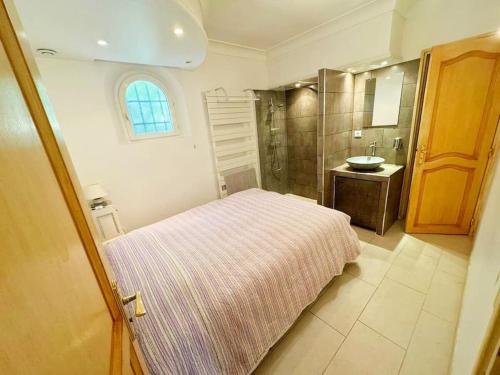 a bedroom with a bed and a bathroom with a sink at Villa Les Reflets - Lac, Vue panoramique, piscine in Montauroux