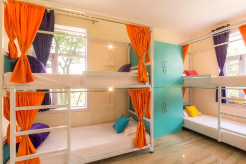 a dorm room with bunk beds with orange curtains at Dormigo in Bīr