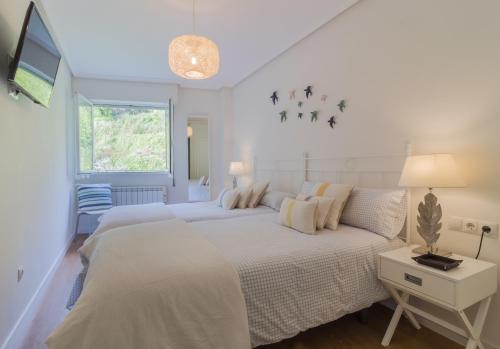 a white bedroom with a large bed and a window at Apart El Muelle Centro de Ribadesella VUT-3752-AS in Ribadesella