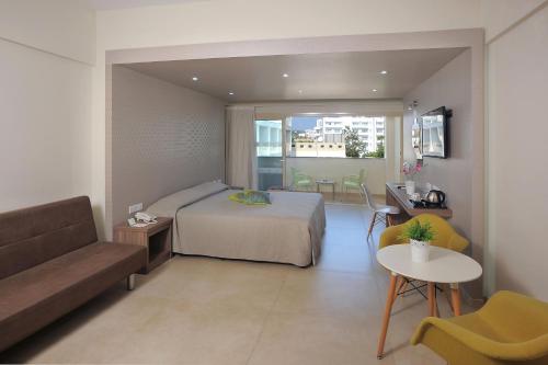 a bedroom with a bed and a couch and a table at Nelia Gardens in Ayia Napa