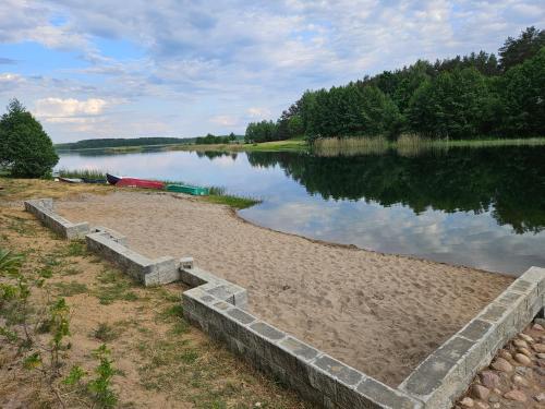 a body of water with a boat on the shore at Ferienhaus JULKA am See mit Kamin & WLAN - Domek Letniskowy JULKA in Teerau