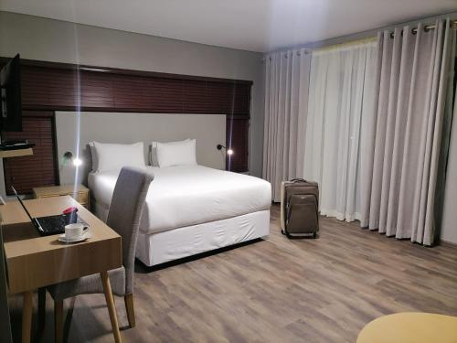 una habitación de hotel con una cama blanca y una maleta en HWH Guesthouse Middelburg en Middelburg