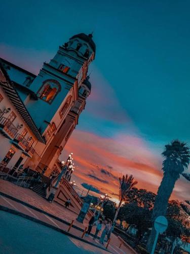 a building with a clock tower with a palm tree at Eco-cabaña piemonte in Guasca