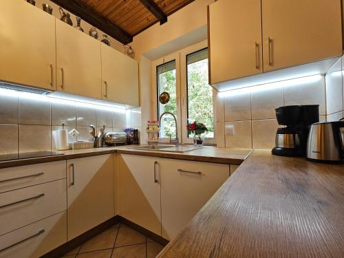 a kitchen with white cabinets and a sink and a window at Ferienhaus JULKA am See mit Kamin & WLAN - Domek Letniskowy JULKA in Teerau