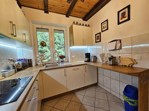 a large kitchen with white cabinets and a sink at Ferienhaus JULKA am See mit Kamin & WLAN - Domek Letniskowy JULKA in Teerau