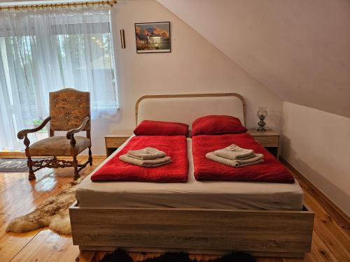a bedroom with a bed with red blankets and a chair at Ferienhaus JULKA am See mit Kamin & WLAN - Domek Letniskowy JULKA in Teerau