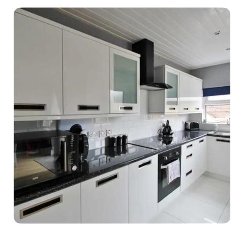 a kitchen with white cabinets and black counter tops at Mournview in Belfast