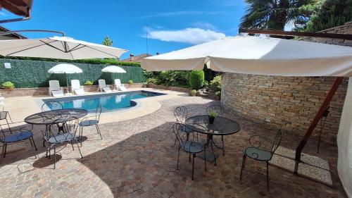 a patio with tables and an umbrella next to a pool at Villa Laura B&B in Fossano