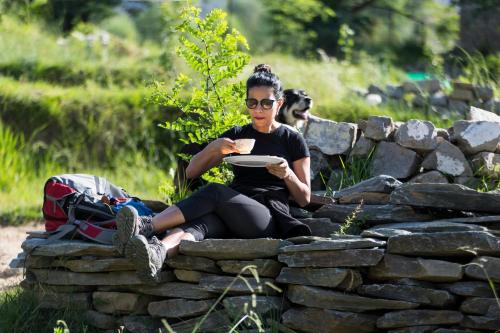 a woman sitting on a rock wall holding a frisbee at Dormigo in Bīr