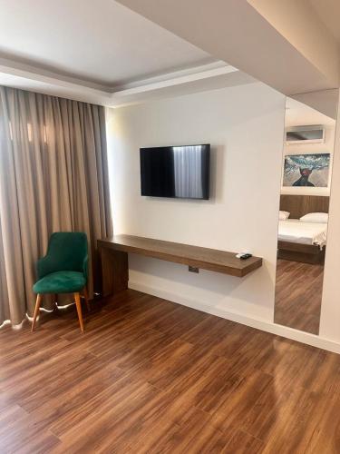 a room with a green chair and a television on a wall at S&S Business Park in Mağusa
