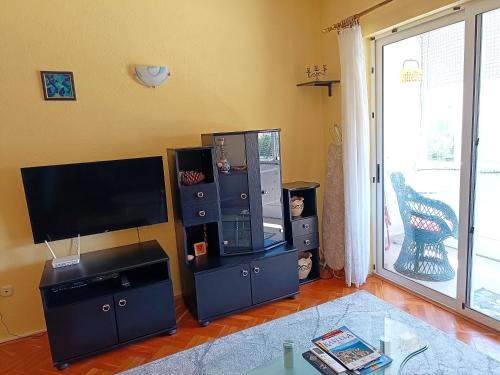 ein Wohnzimmer mit einem Flachbild-TV und einem Entertainment-Center in der Unterkunft Apartment near beach with free parking in Kaštela