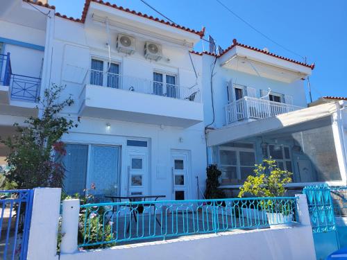 ein weißes Haus mit einem blauen Zaun davor in der Unterkunft Antonys Apartment Sea View II (1st floor) in Tiros
