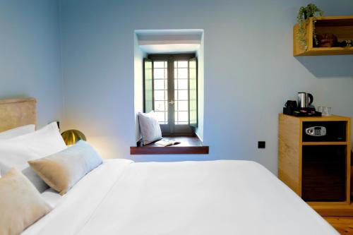 a bedroom with a white bed and a window at Kenta Mountain Hotel & Gastrobar in Portariá