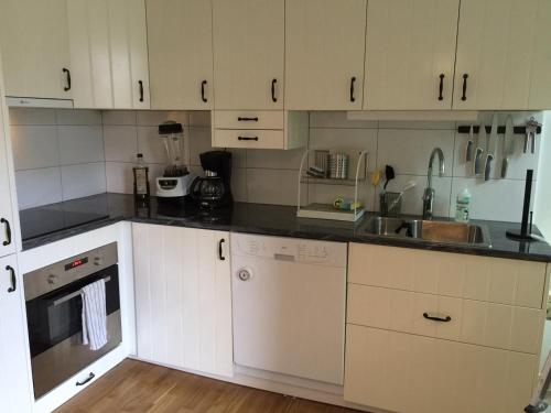 a kitchen with white cabinets and black counter tops at Björnnästet med havsutsikt innanför murarna in Visby