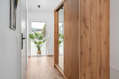a hallway with a wooden door and a potted plant at Apartamenty Pod Cisem Lux in Kudowa-Zdrój