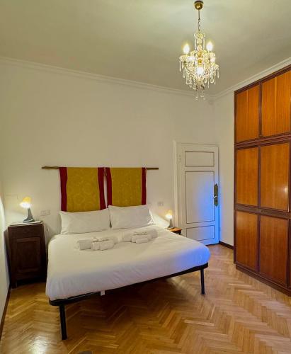 Un dormitorio con una gran cama blanca con una lámpara de araña. en La Dolce Vita, en Pisa