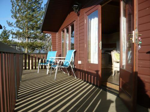 BrooklandにあるSpacious cottage with sauna looking out on astonishing grasslandsの家の上に椅子とテーブル付きのデッキ