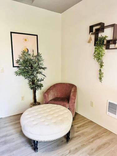 a living room with a chair and a white ottoman at Soleil Salem in Salem