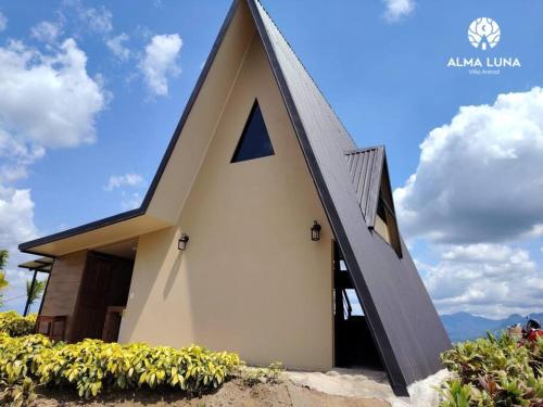a small house with a pointed roof and flowers at Alma Luna Villa Arenal in Monterrey