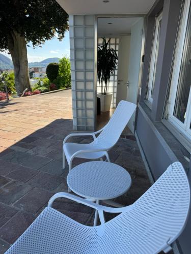 two white chairs and a table on a porch at Veralto - Modern Suite with Como Lake view in Vacallo