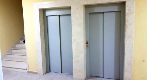 three elevator doors in a building with a staircase at R-RESIDENCY Tower in Banja Luka