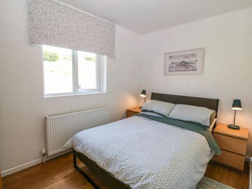 a bedroom with a bed and two windows at Ty Bach in Caernarfon