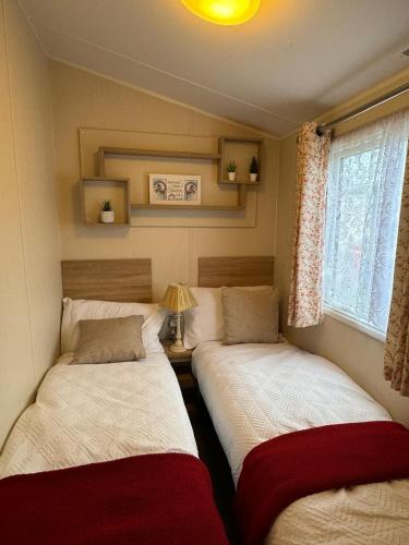 two twin beds in a room with a window at Modern & Blissful Beach Park Holiday Home in Dovercourt, Essex, in Parkeston