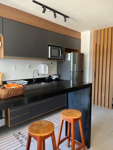 eine Küche mit einer schwarzen Theke und 2 Hockern in der Unterkunft AP Cantinho baiano Ilhéus Ba in Ilhéus