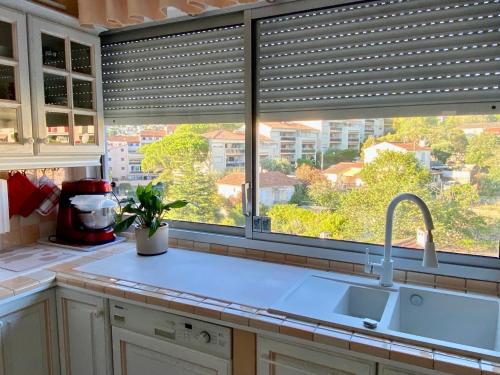 une cuisine avec évier et une fenêtre avec stores dans l'établissement L'oasis de Vallauris, piscine, parking privé, à Vallauris