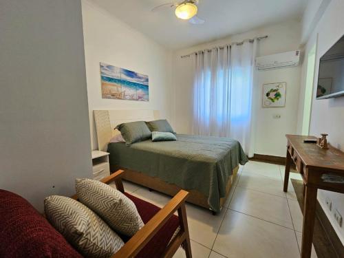 a bedroom with a bed and a couch and a table at Frente Mar! Apartamento TOP, experiência única! in Guarujá