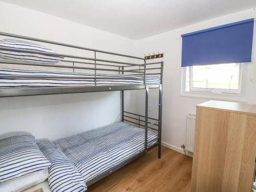a bedroom with two bunk beds and a window at Lletyr Bugail in Caernarfon