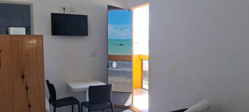 a room with a table and chairs and a television at Pousada Vela Mar in Maragogi
