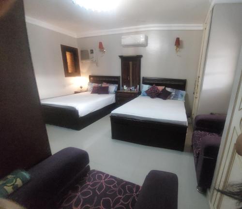 a small room with two beds and a chair at Marina 4 Guest House in El Alamein