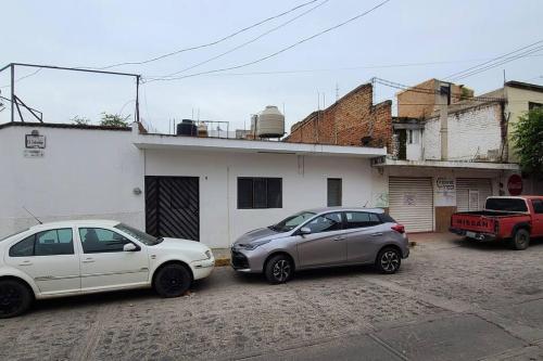 two cars parked in front of a white house at Casa Habitación Frida Valentina in Tequila