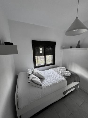 a white bedroom with a bed with a window at Alcarria , Casa del Agua in Albalate de Zorita