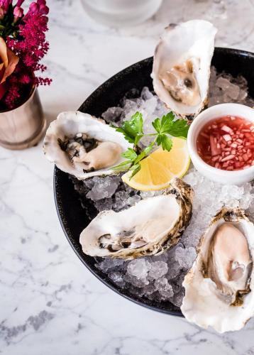 a plate of oysters on ice with salsa and flowers at The Westbury Hotel in Dublin