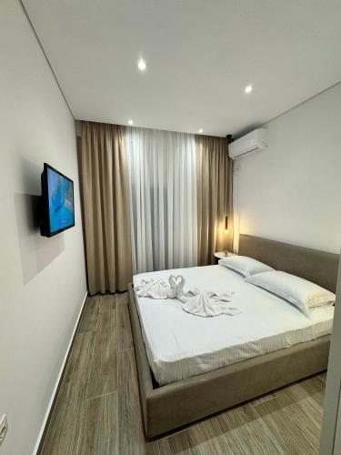 a bedroom with a bed and a tv on a wall at Elysian Escape Apartment in Sarandë