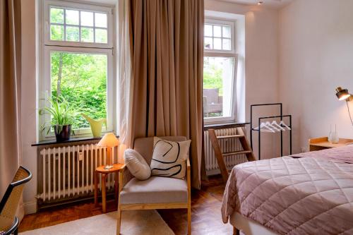 um quarto com uma cama, uma cadeira e uma janela em Apartment mit 2 Schlafzimmern am Bergpark Wilhelmshöhe em Kassel