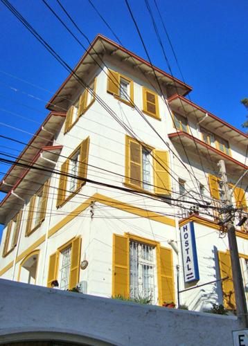 a white building with yellow shutters on it at Hotel Paseo Valle in Viña del Mar