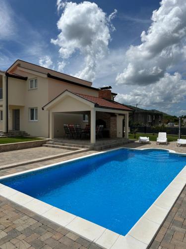 a blue swimming pool in front of a house at Guest House Ana Marija in Ljubuški