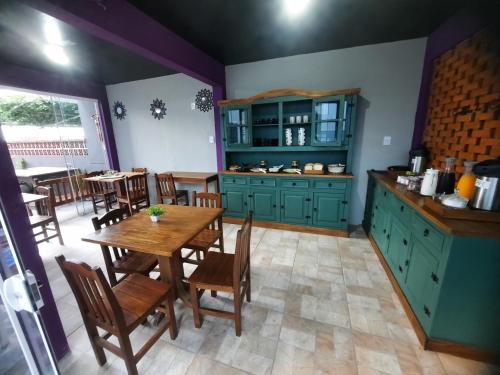 a kitchen with green cabinets and a wooden table at Pousada Casa da Maga - Vila Germânica in Blumenau