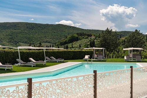 a swimming pool with chairs and a fence at Cappuccina Country Resort in San Gimignano