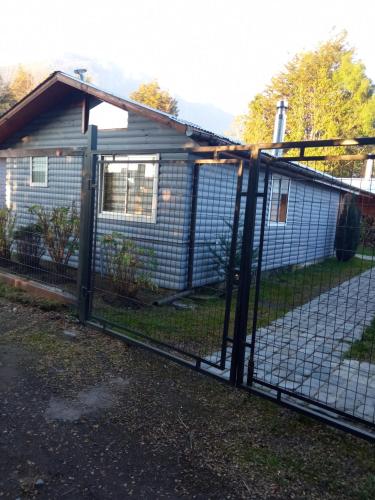 a chain link fence with a gate in front of a house at Cabaña Gloria in Coñaripe