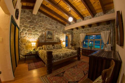 um quarto com uma cama e uma parede de pedra em Hotel Rancho San Cayetano em Zitácuaro
