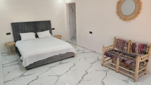 een slaapkamer met een bed en een stoel op een marmeren vloer bij ferme privé avec piscine in Safi