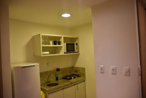 a kitchen with a white refrigerator and a microwave at Studio Moderno bem localizado in Feira de Santana