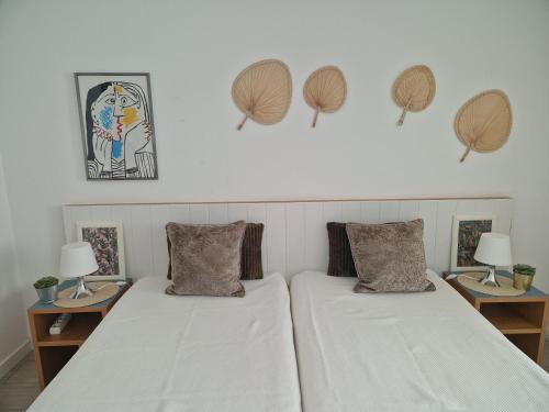 a bedroom with two beds and two tables with lamps at Apartamentos Dom Henrique in Monte Gordo